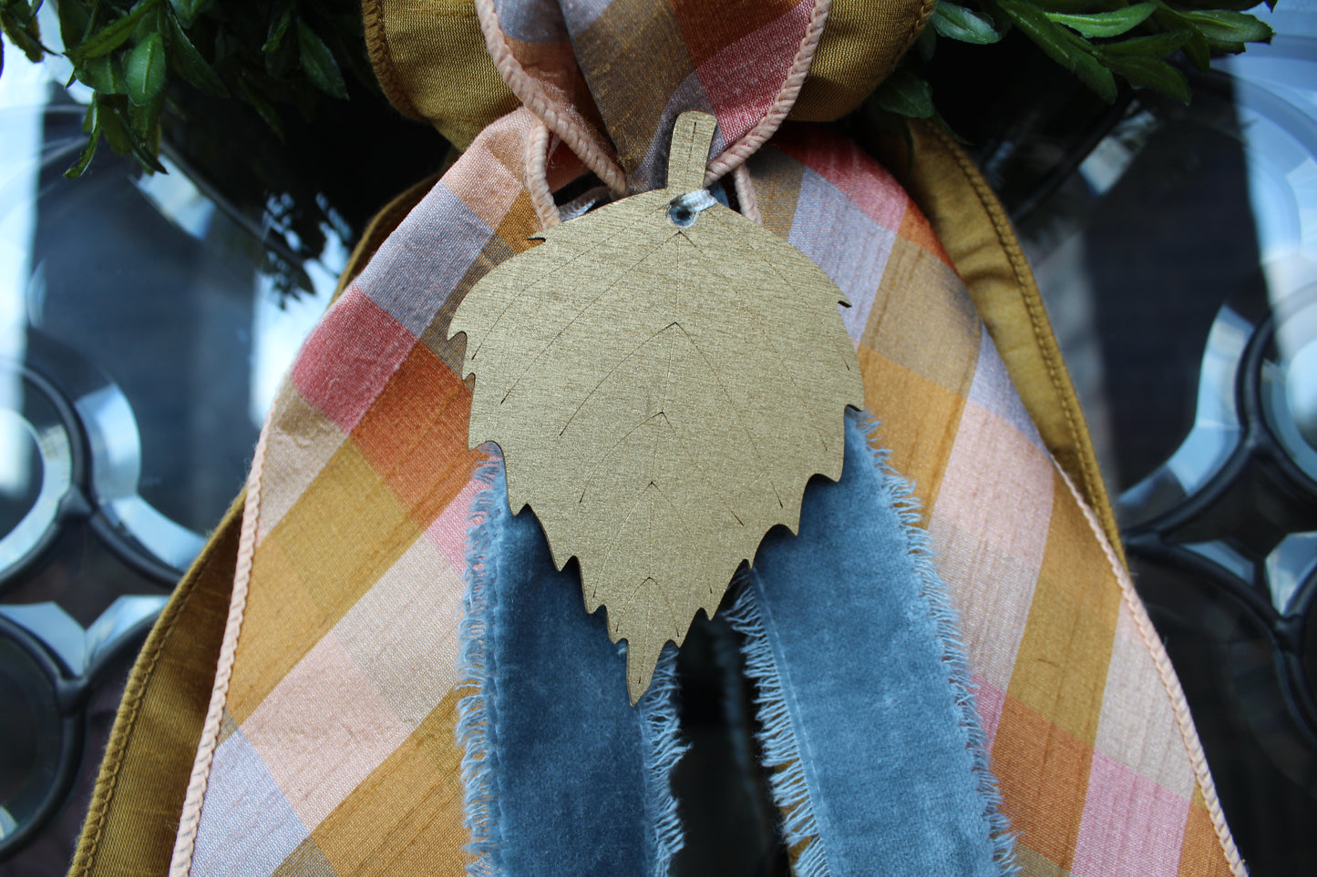 Decorative leaf ornament on a plaid ribbon with a blurred background
